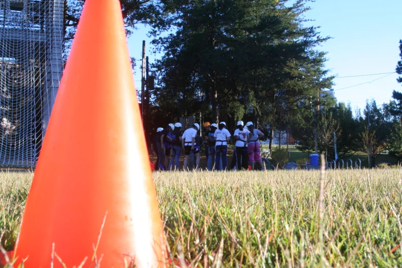 a group of people in a grassy field next to a cone