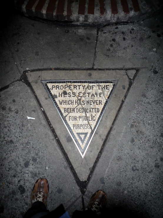 man stands next to a triangular shaped floor sign