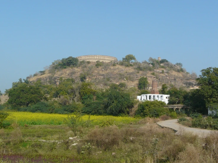 the mountain is behind the field with a house on top