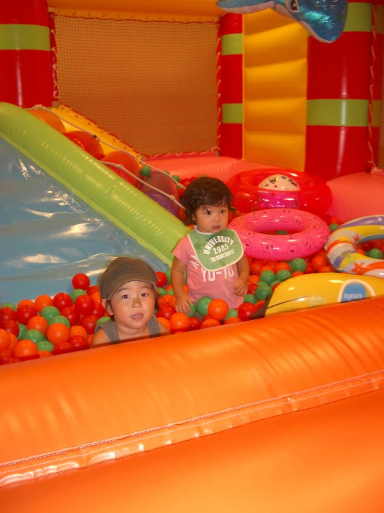 two children in a bouncy house with some balls on it