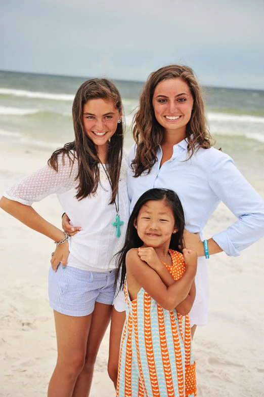 two girls standing in the sand with a cross on