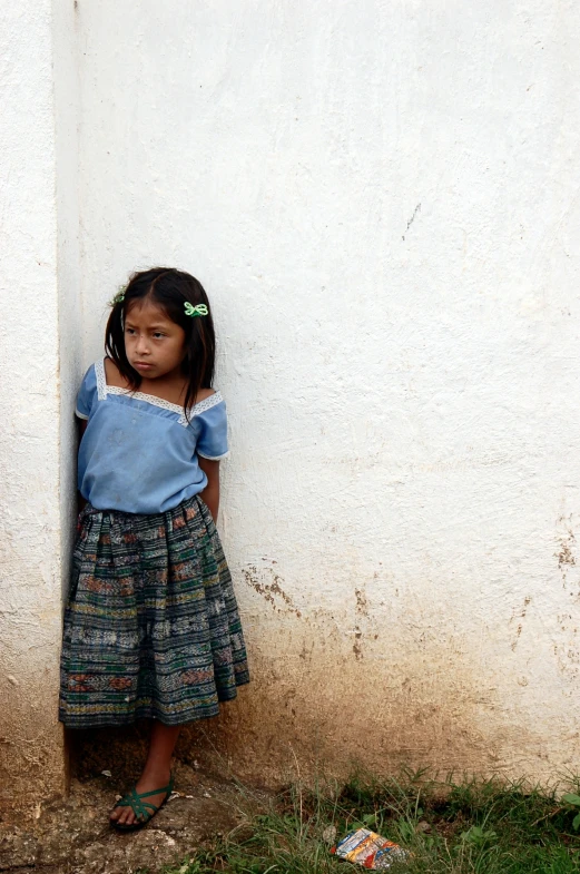 a little girl stands near a wall in an unplugged place