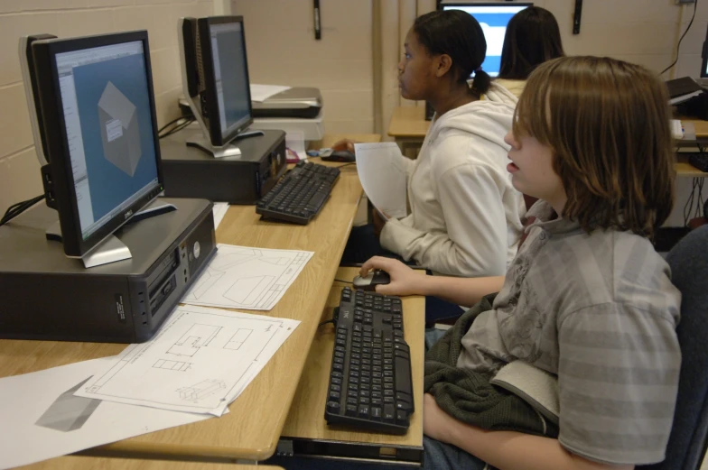 a little girl sitting at a desk with a computer on it