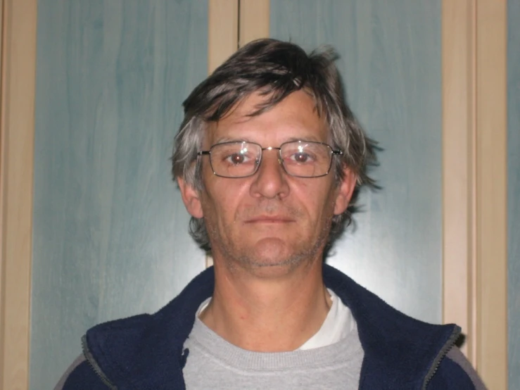 a man with glasses is posing in front of the camera