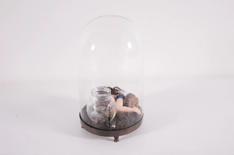 a miniature model girl standing in a glass ball with her back to the camera