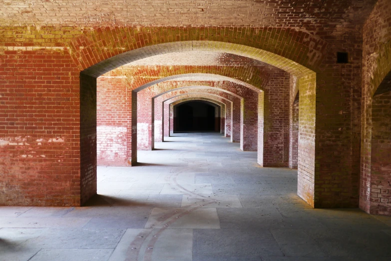 long brick lined hallway leading to light from one light