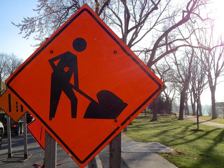 a construction sign with an orange work sign behind it