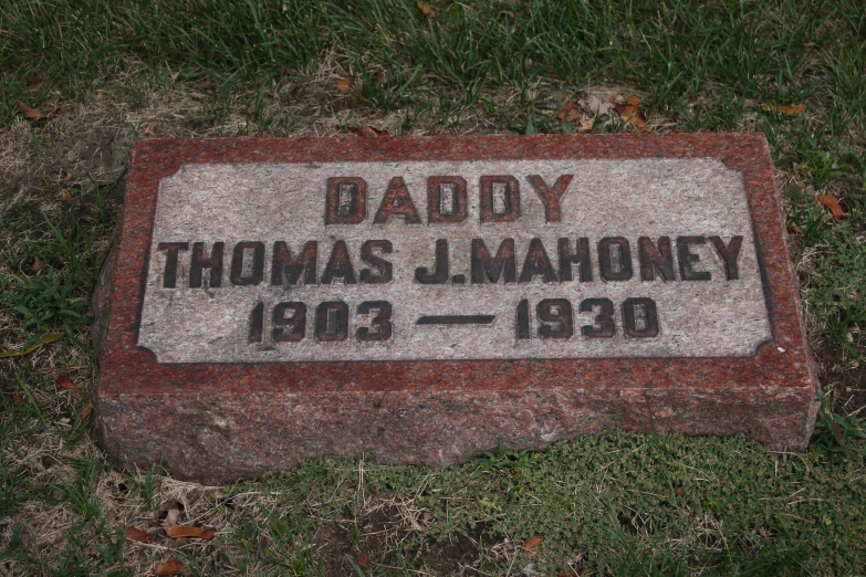 a tombstone stone in a grassy area with the names of people and letters etched into it