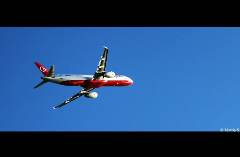 a red and white airplane flying in the sky