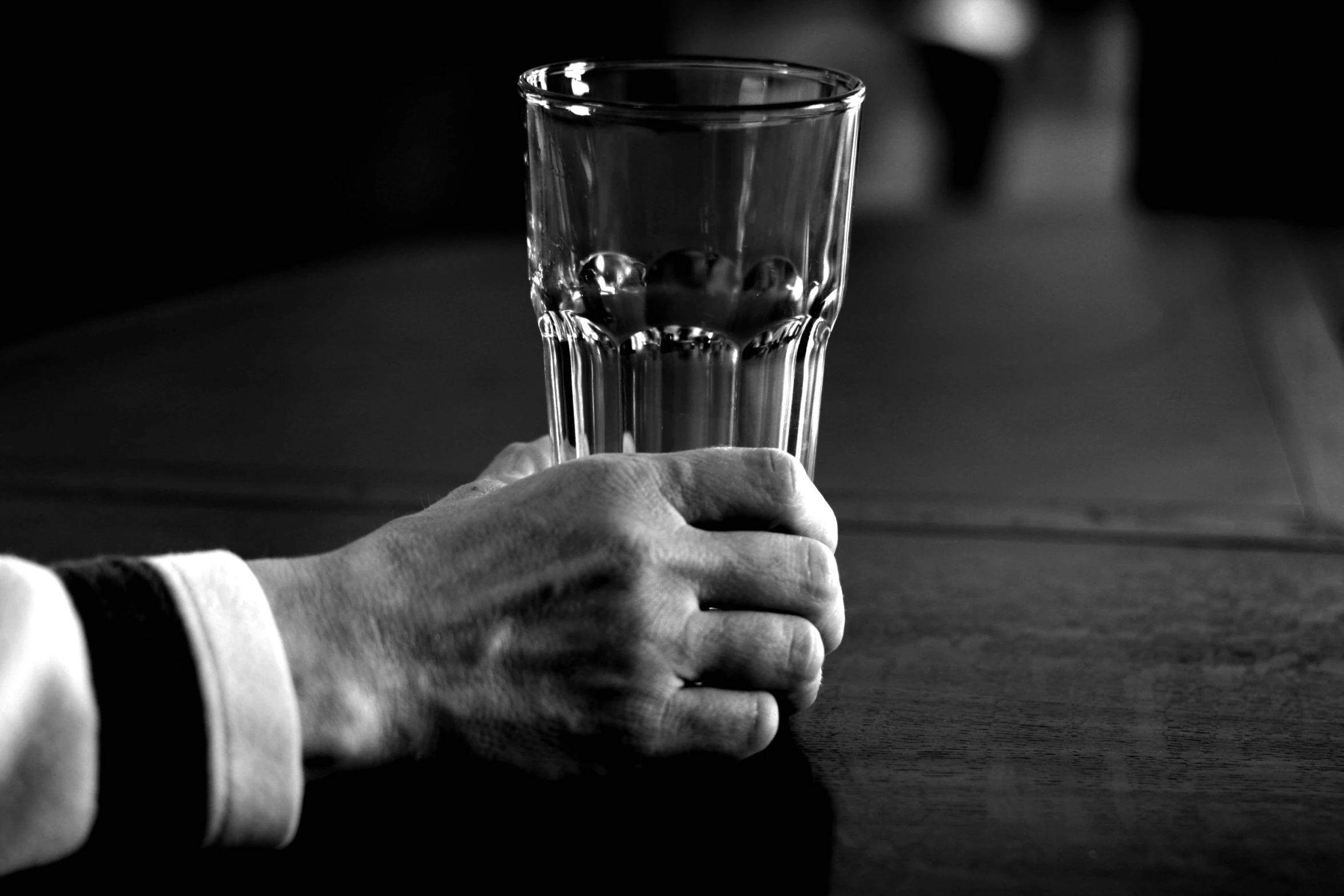 the hand of a person holding a glass of water