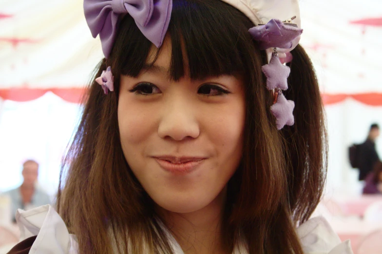 a woman wearing purple bows smiling with people in the background