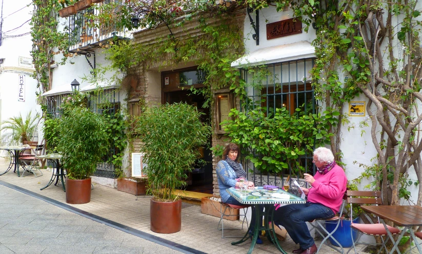 two elderly people at tables outside of a building