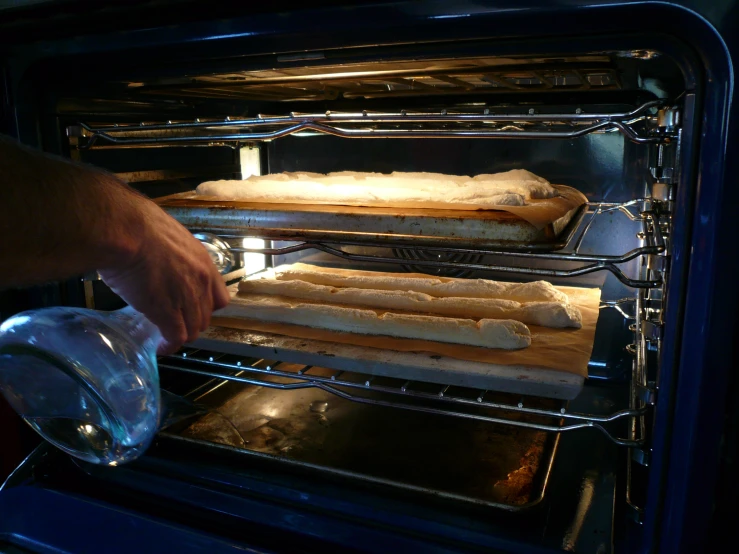 a person is putting their baking trays into an oven