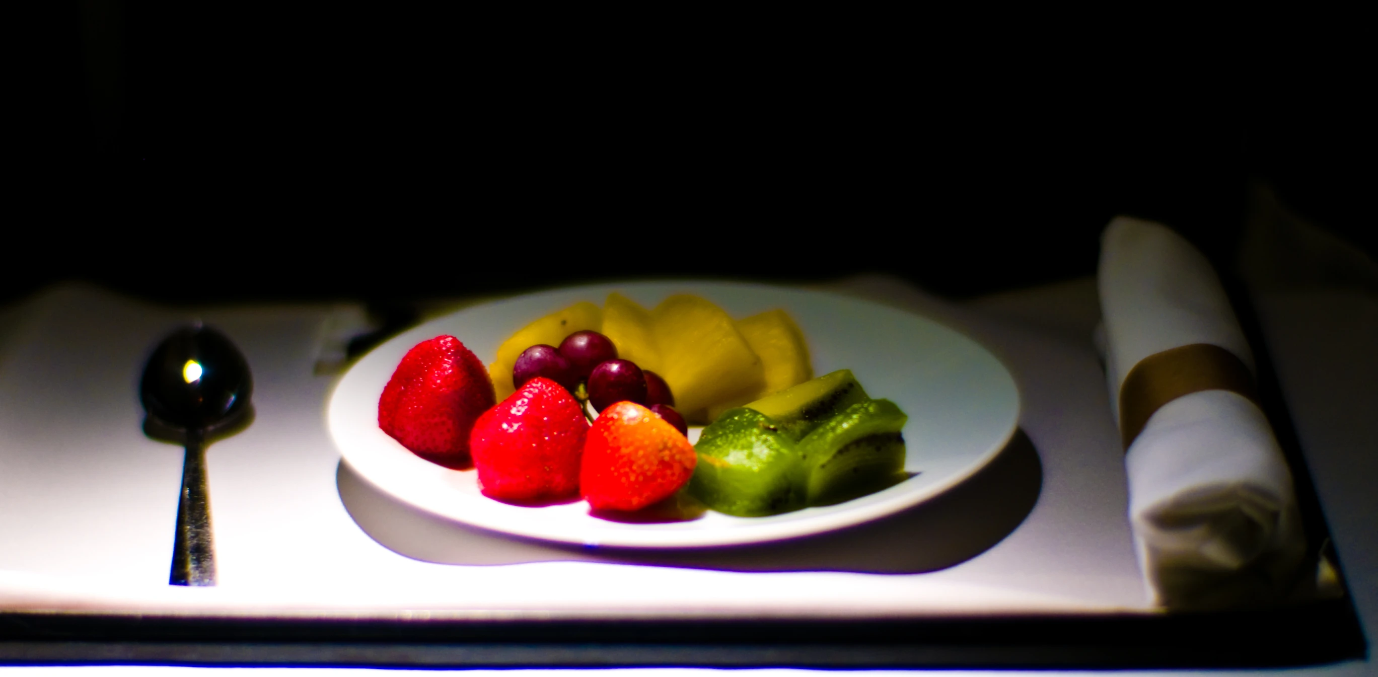 there is fruit that is on the plate next to a spoon