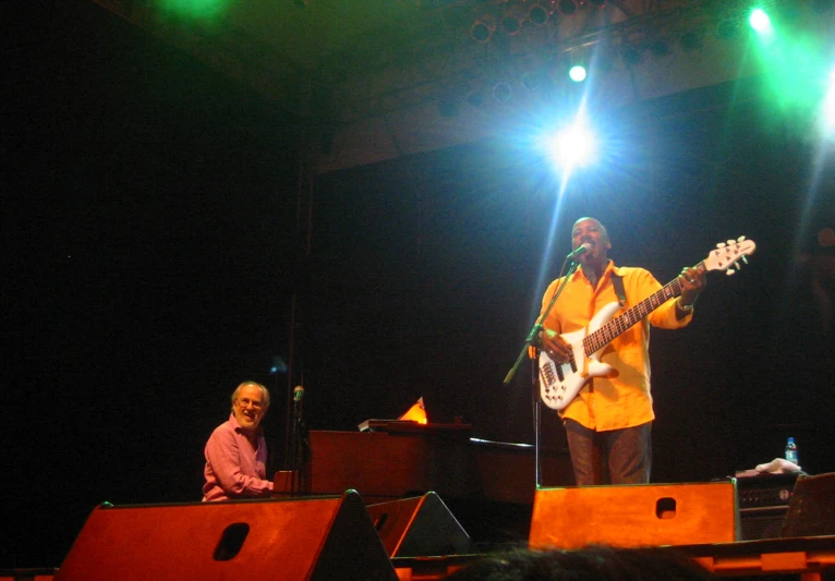 two men playing guitar and singing with two other men in the background