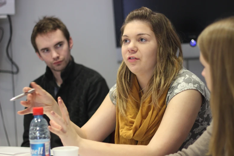 three people sitting down talking at a table