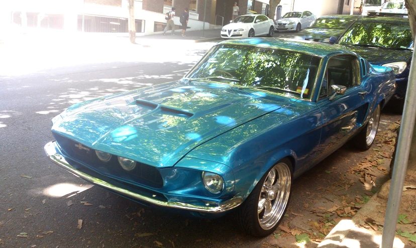 a very pretty blue car in a busy street