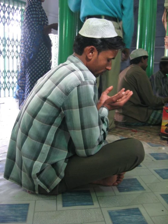 a man in plaid shirt kneeling down with hands clasped