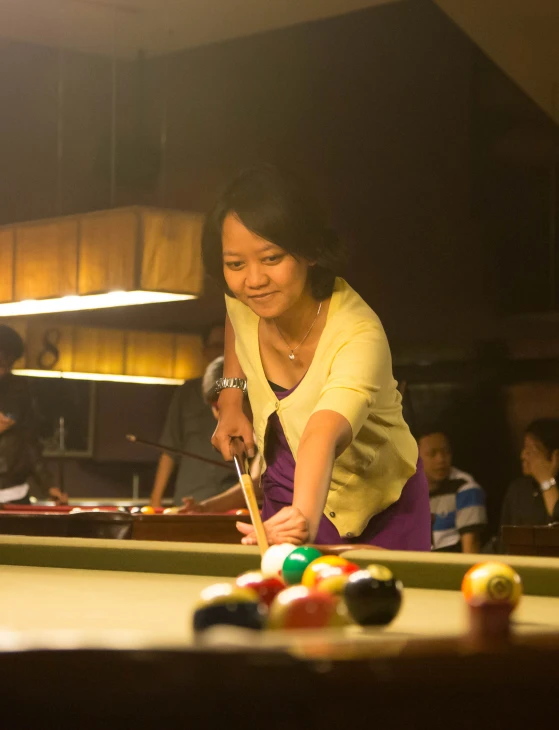 a lady playing a game of pool on a billiards table