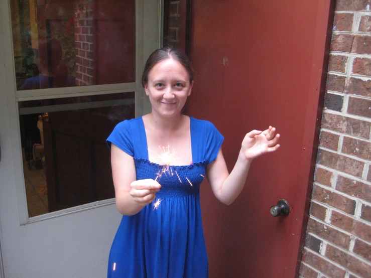 a girl in a blue dress smiles next to a red door