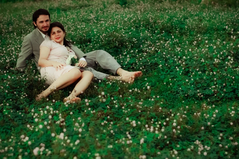 a man and woman sitting together in a field