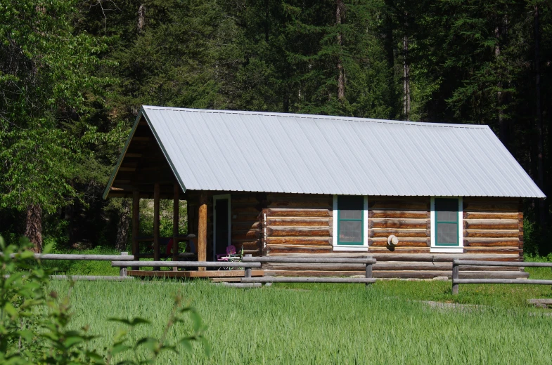 a log cabin with grass and trees around it