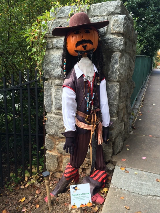 a scarecrow wearing a costume is next to the gate