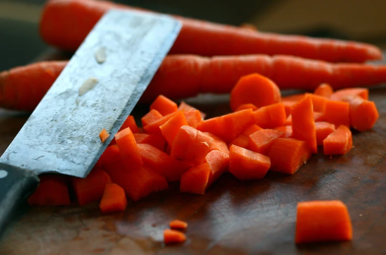 a pile of carrots being chopped by a knife