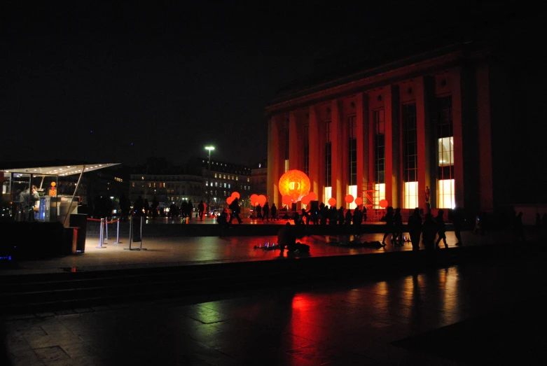 people stand in front of a building at night