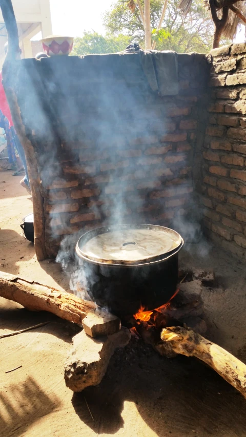 a man sitting on top of a brick structure while cooking soing