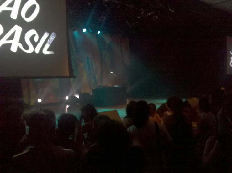 group of people standing in front of a projection screen at night