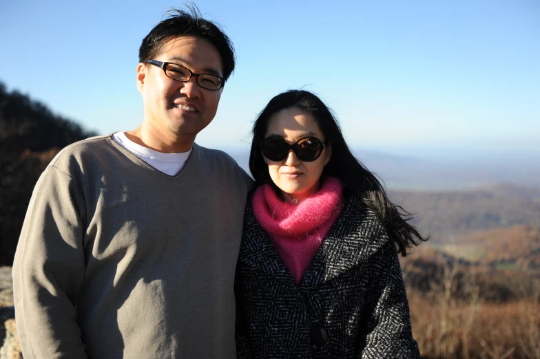 two people standing next to each other on top of a hill