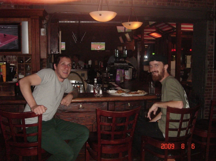 two men sitting next to each other at a bar