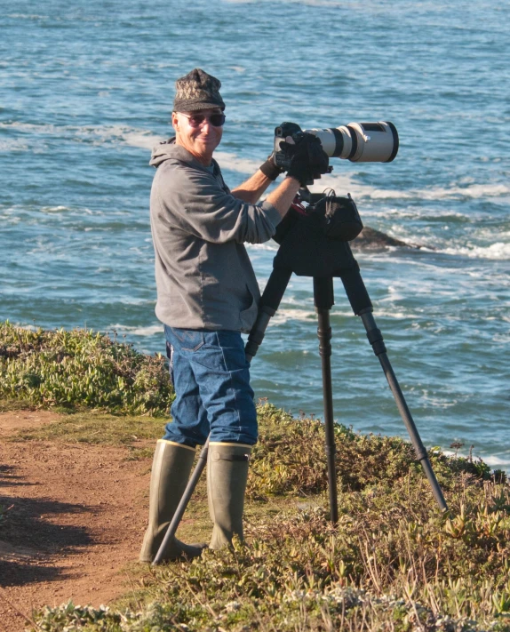 a man standing on top of a hill next to a camera