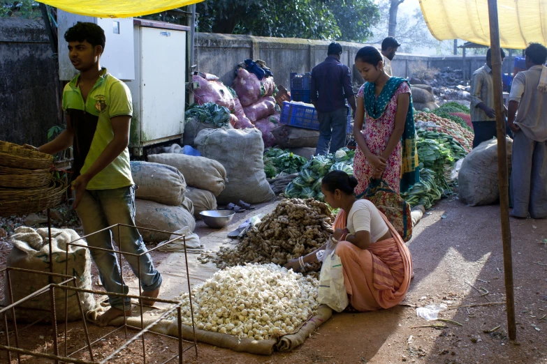 a group of people standing around bags of vegetables and grains