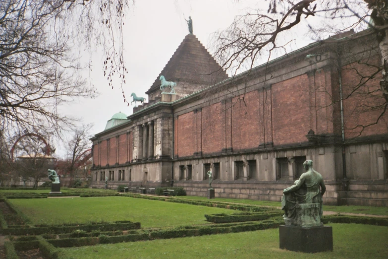 a sculpture of an angel on a lawn in front of a building