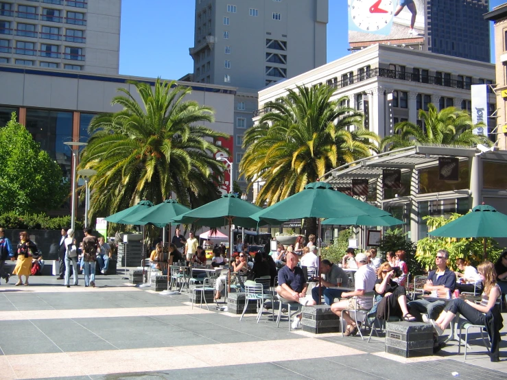 a group of people are sitting at tables outside in a city