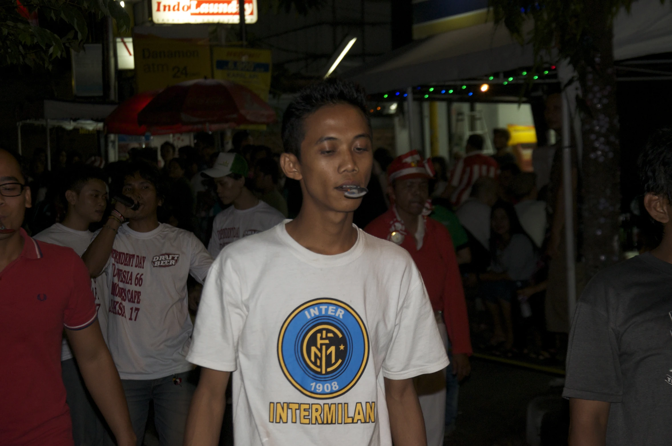 a young man blowing bubbles on his nose in a crowded street