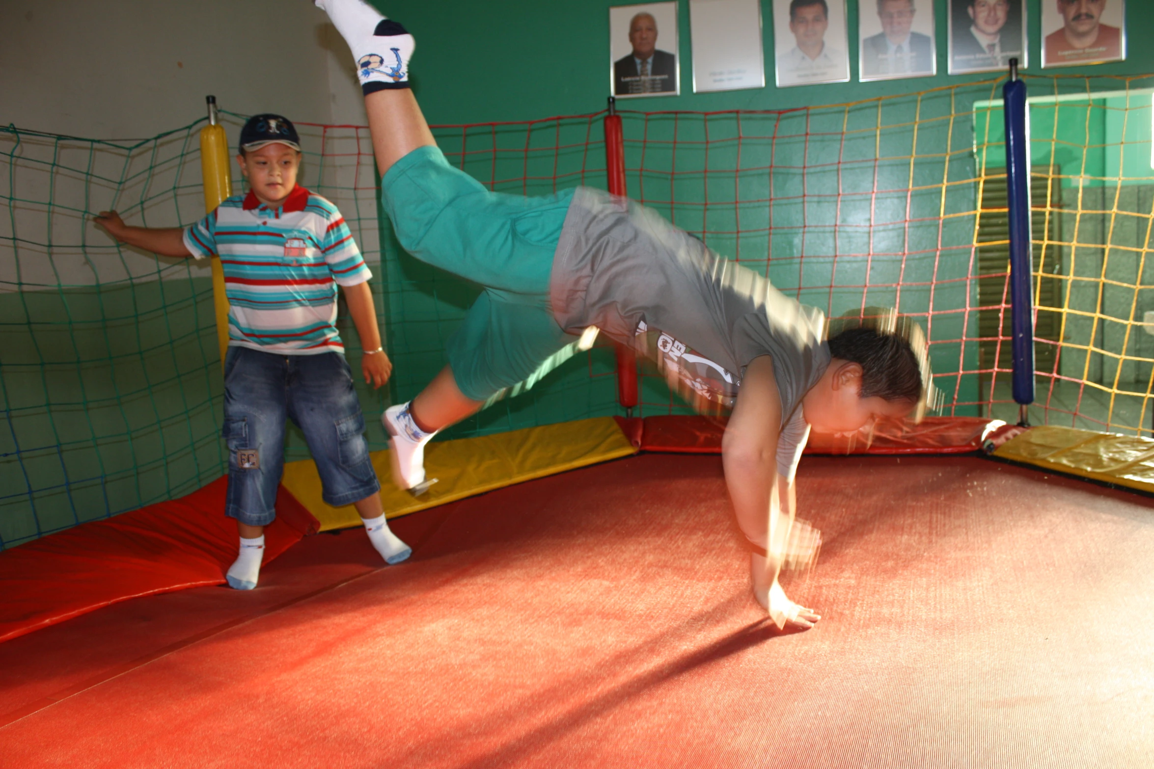 a young man in blue shorts diving off a trampoline