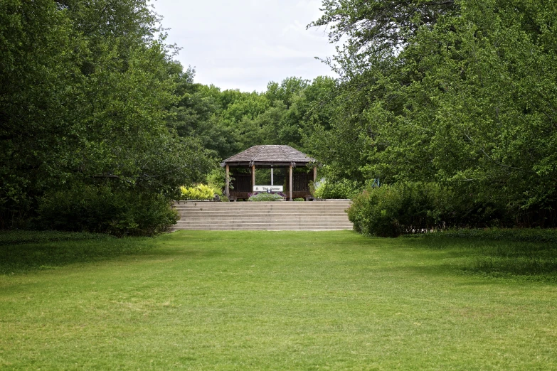 an old pavilion surrounded by green grass and trees