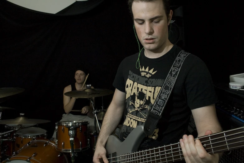 a young man playing the bass guitar while wearing a t - shirt