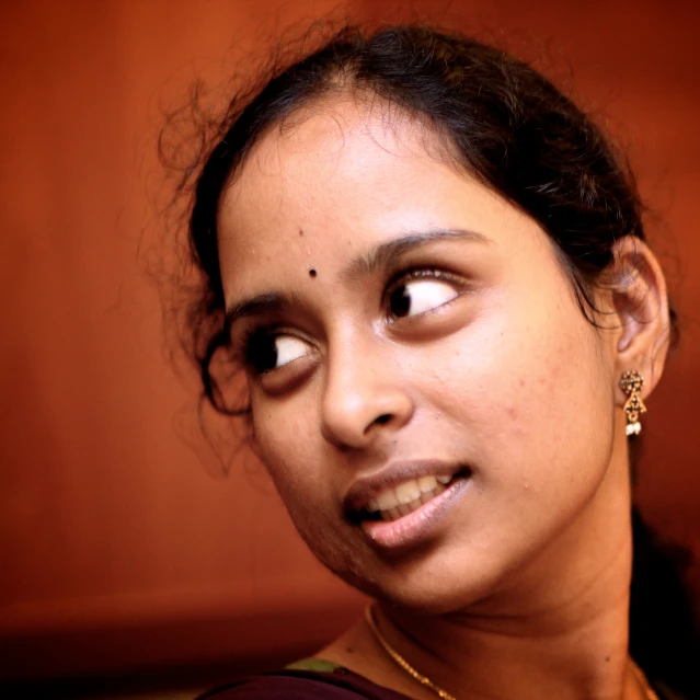 a woman standing in front of a wall with one eye open