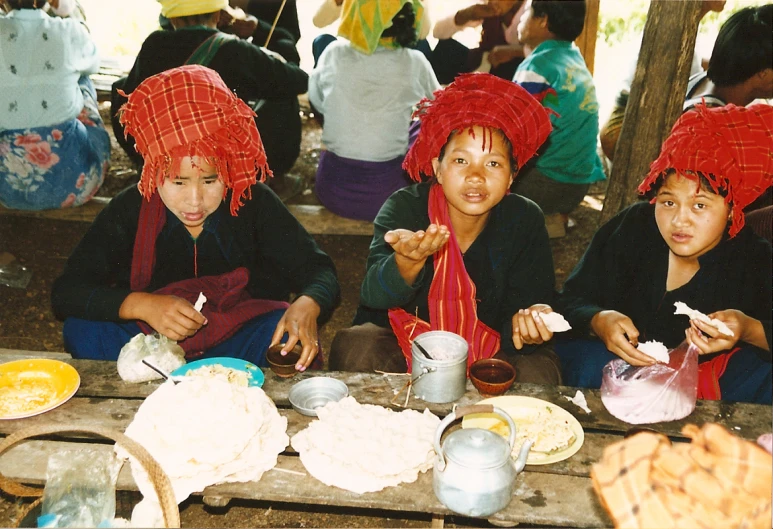 people wearing elaborate hats and eating food together