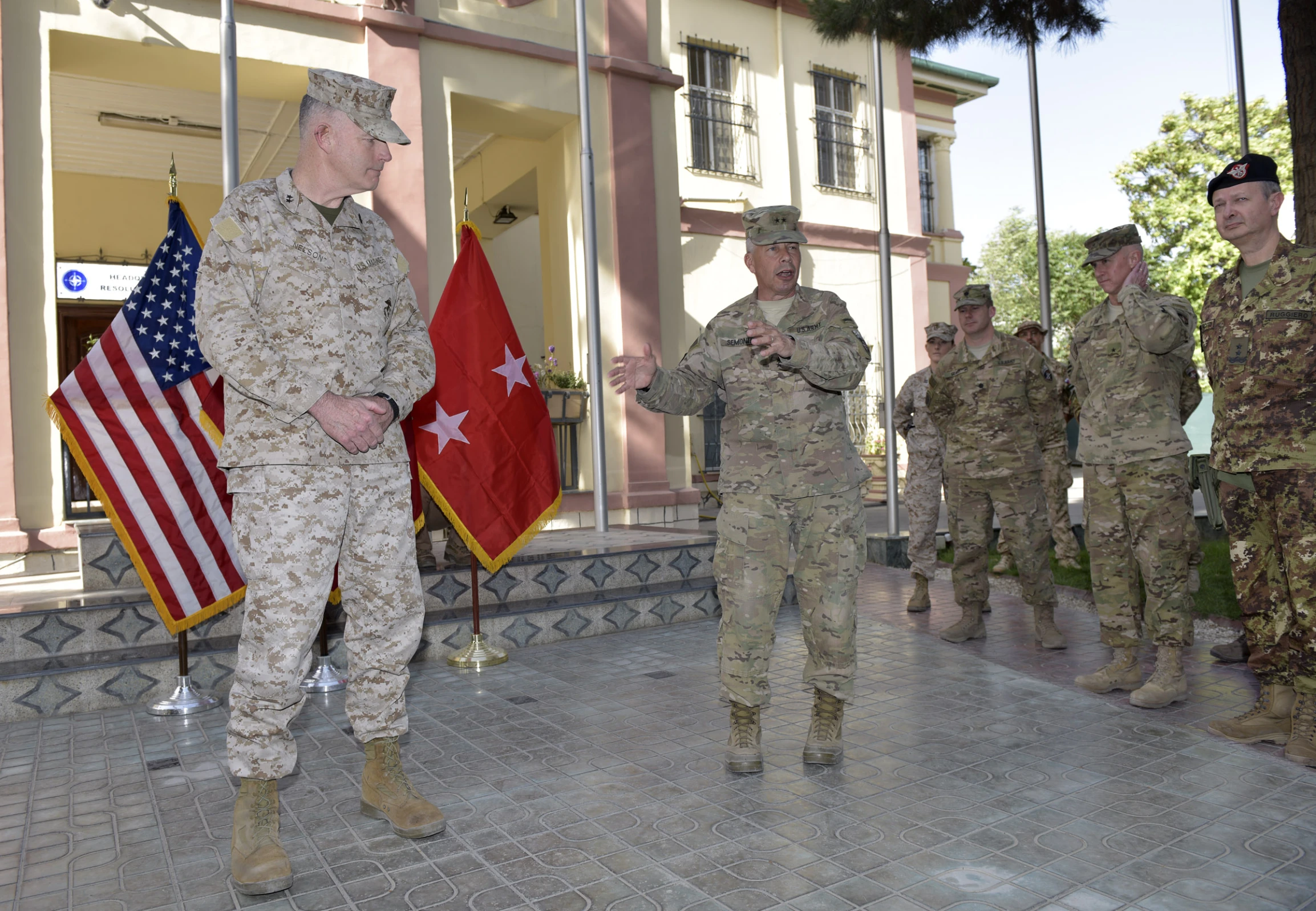 a military commander holds his arm out in front of some other soldiers