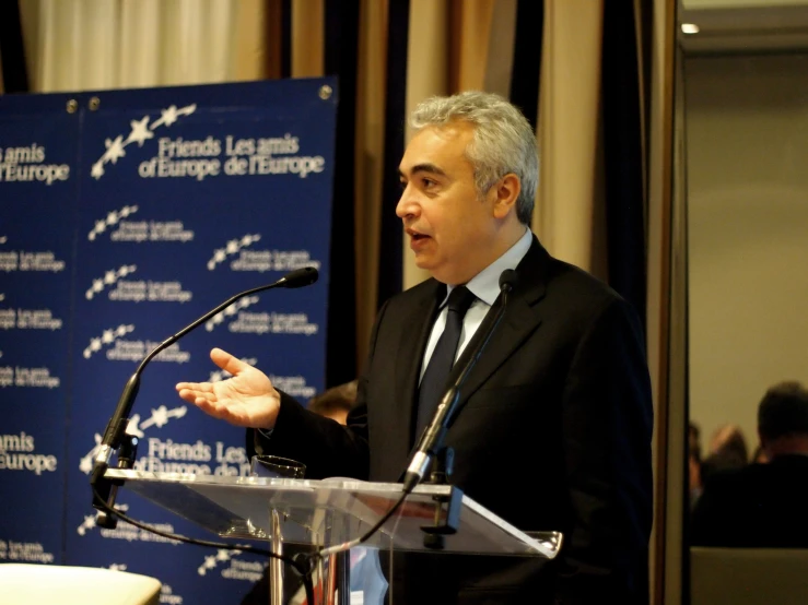 a man in a suit speaking from the podium