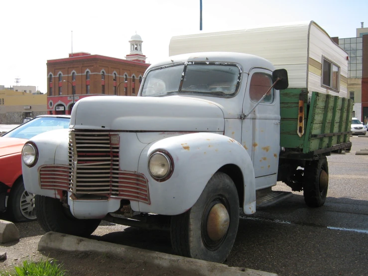 an old green and white truck parked next to other cars