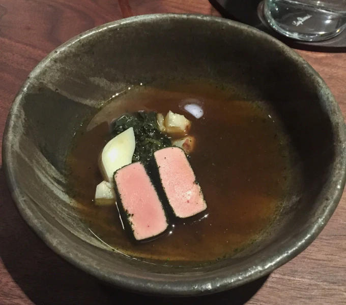 small pieces of meat sit in an elaborate bowl of broth