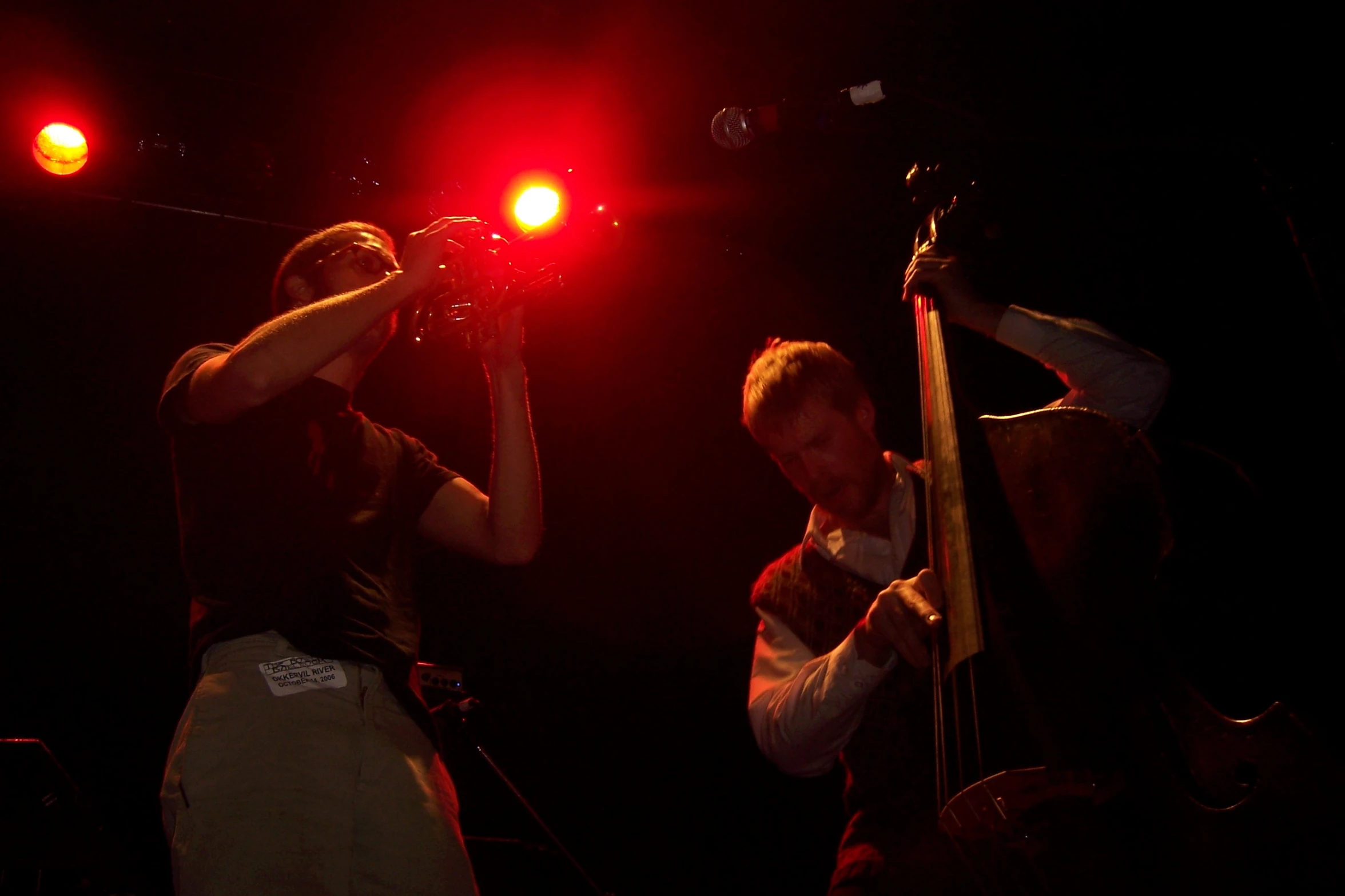 two men in dark lighting on stage at a music event