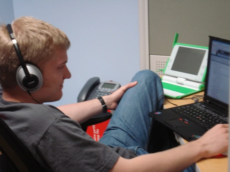 a boy using a laptop and listening to music