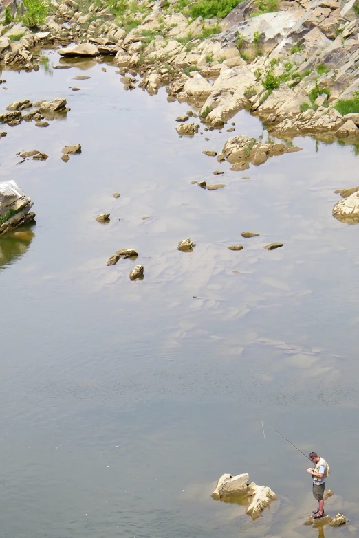 a man standing in shallow water while holding a fish